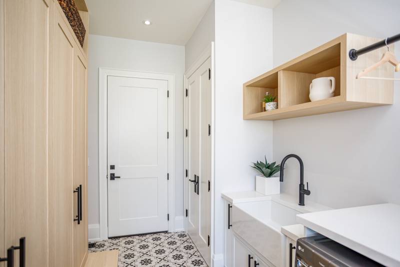 Stock two-panel shaker door featured in a modern laundry room, showcasing a clean white panel design paired with sleek black hardware.