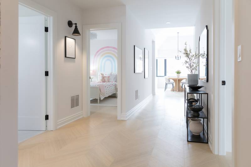 Bright modern hallway with transitional moulding, a step bevel profile, white interior wood doors and natural wood flooring